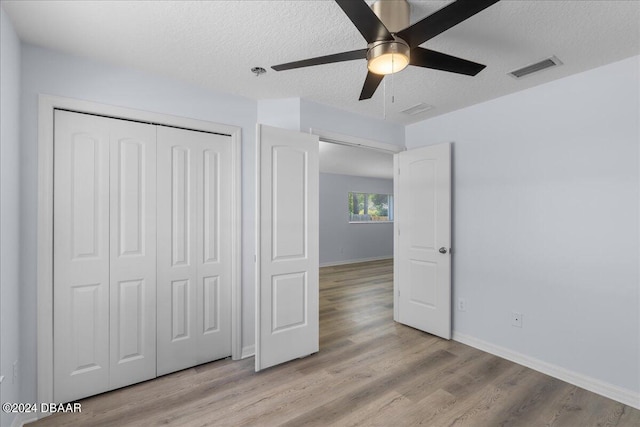 unfurnished bedroom with visible vents, a textured ceiling, a closet, light wood finished floors, and baseboards