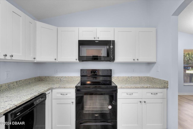 kitchen with black appliances, white cabinets, light stone countertops, and lofted ceiling