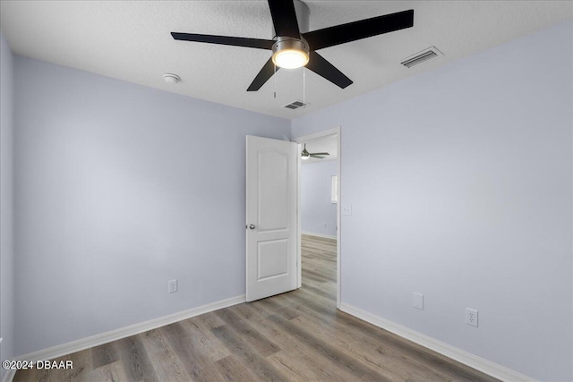 spare room with visible vents, baseboards, wood finished floors, and a ceiling fan