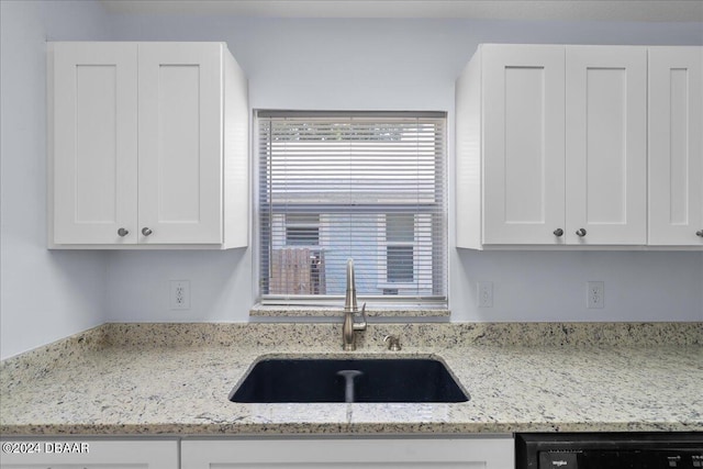 kitchen featuring white cabinetry, dishwasher, light stone countertops, and a sink