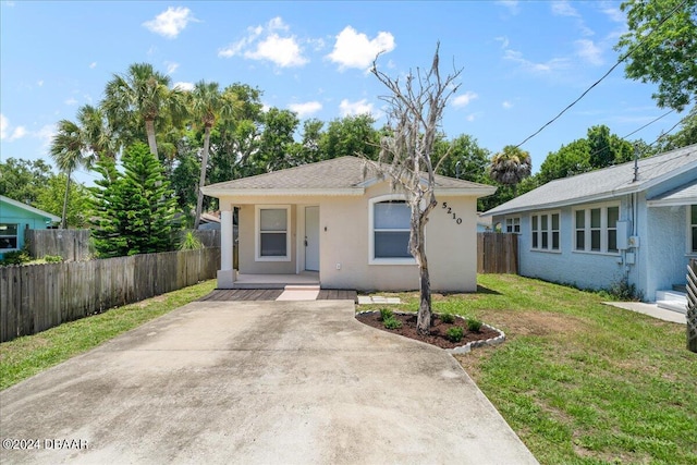 bungalow-style house featuring stucco siding, a porch, a front yard, and fence