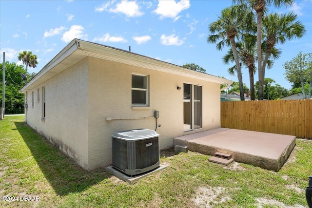 back of property with central air condition unit, stucco siding, fence, a yard, and a patio area