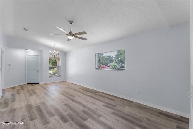 unfurnished room featuring baseboards, visible vents, lofted ceiling, light wood-style floors, and a textured ceiling