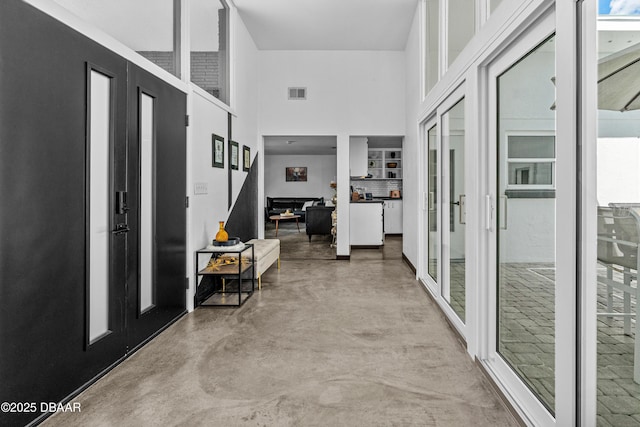 hall featuring finished concrete floors and a towering ceiling