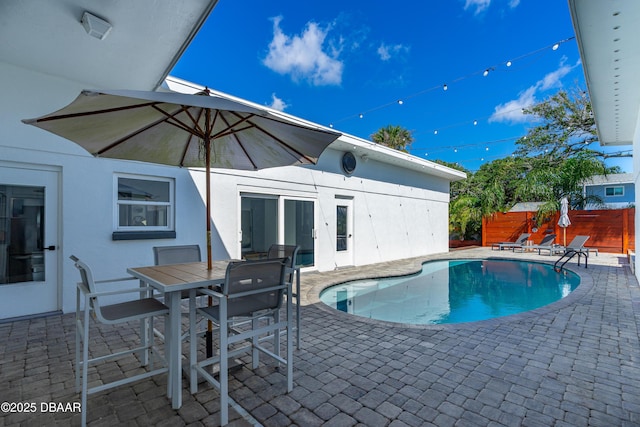 view of swimming pool featuring fence, a patio, and outdoor dining space