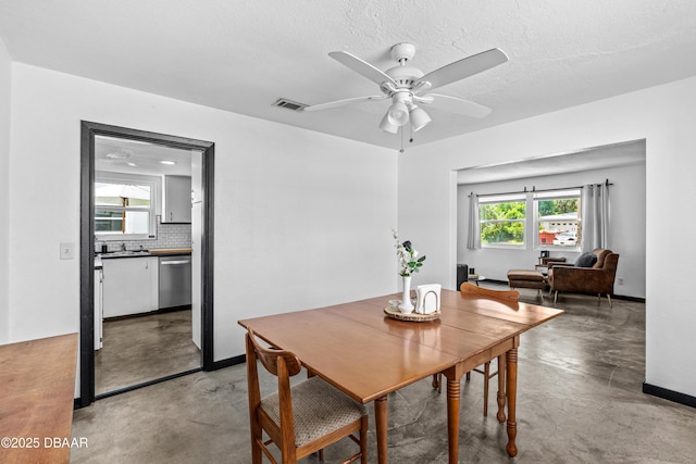 dining space with finished concrete flooring, healthy amount of natural light, a ceiling fan, and baseboards