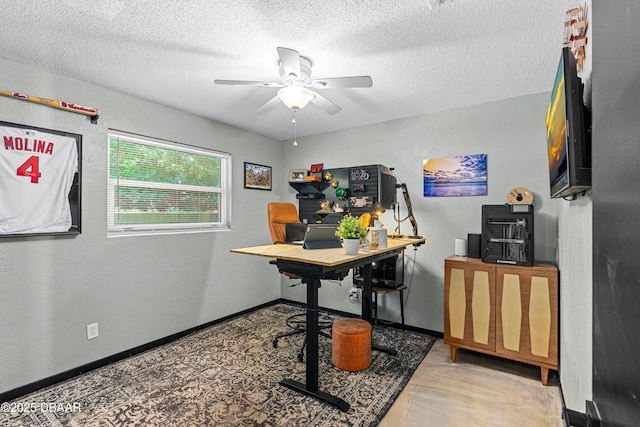 office area featuring ceiling fan, a textured ceiling, a textured wall, and baseboards