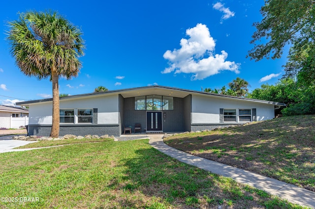 mid-century modern home featuring stucco siding and a front yard