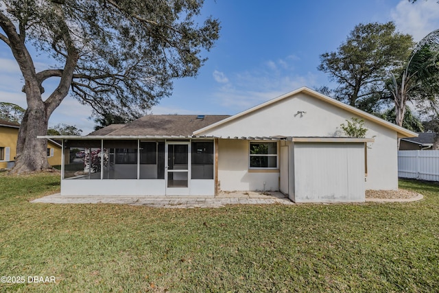 rear view of property featuring a yard, fence, stucco siding, and a sunroom