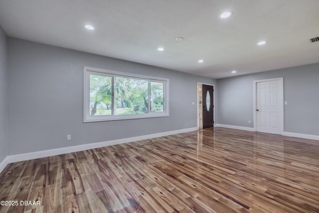 spare room featuring wood finished floors, recessed lighting, baseboards, and visible vents