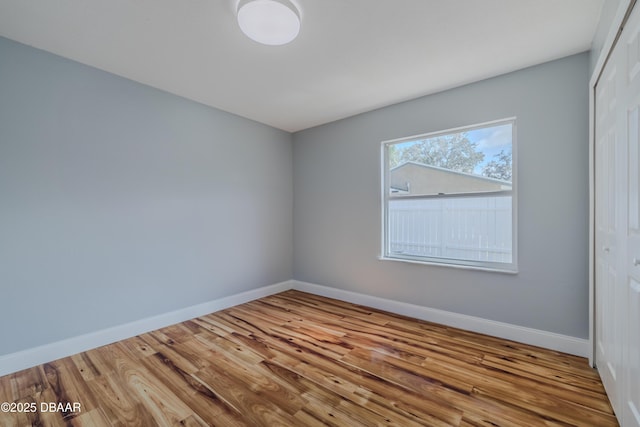 spare room with baseboards and wood finished floors