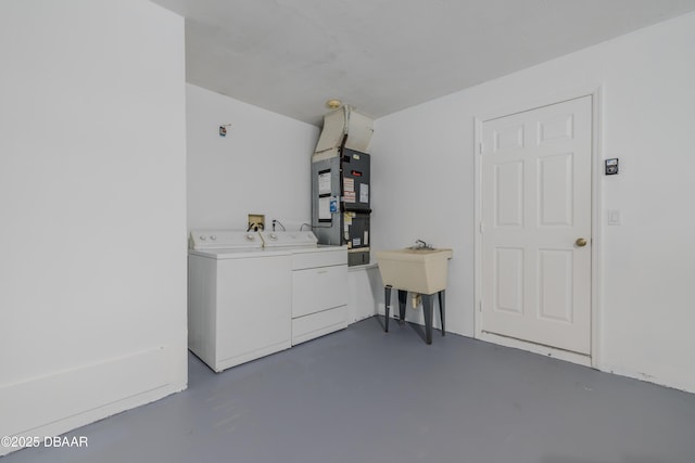 washroom with laundry area, heating unit, washing machine and dryer, and a sink