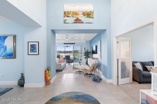 entrance foyer featuring baseboards, ceiling fan, a high ceiling, and light tile patterned floors