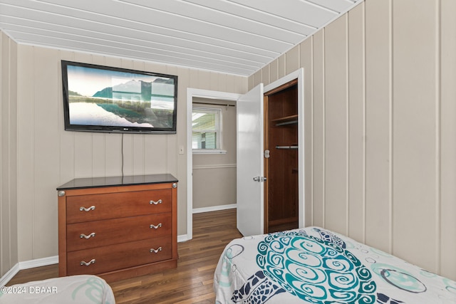 bedroom featuring wooden walls, a closet, and dark hardwood / wood-style flooring