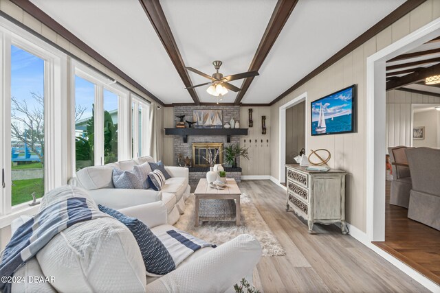 living room with lofted ceiling with beams, ornamental molding, a fireplace, ceiling fan, and light hardwood / wood-style flooring