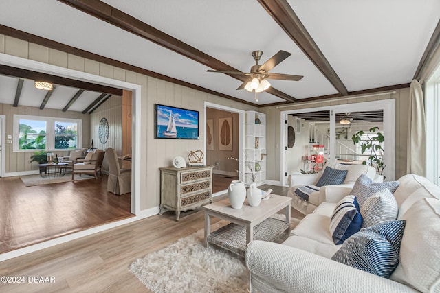 living room featuring lofted ceiling with beams, wooden walls, ceiling fan, and light hardwood / wood-style flooring