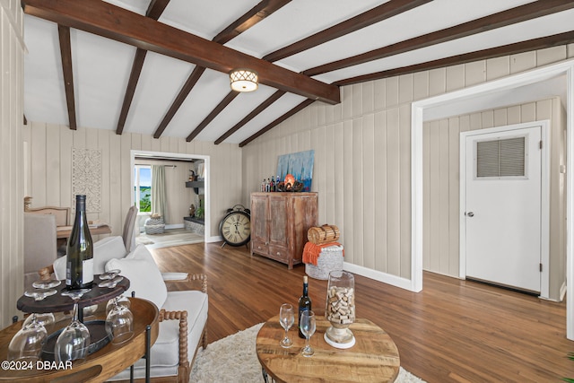 living room featuring wood walls, hardwood / wood-style flooring, and vaulted ceiling with beams