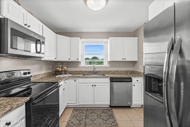 kitchen with white cabinets, stainless steel appliances, sink, and dark stone countertops