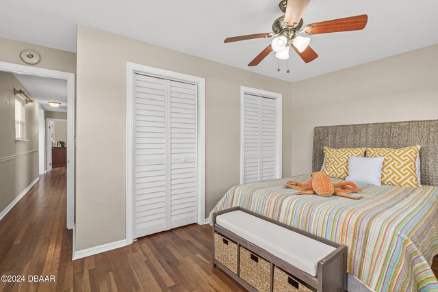 bedroom featuring dark wood-type flooring, two closets, and ceiling fan