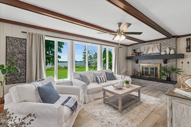 living room featuring a brick fireplace, light wood-type flooring, ceiling fan, and beam ceiling