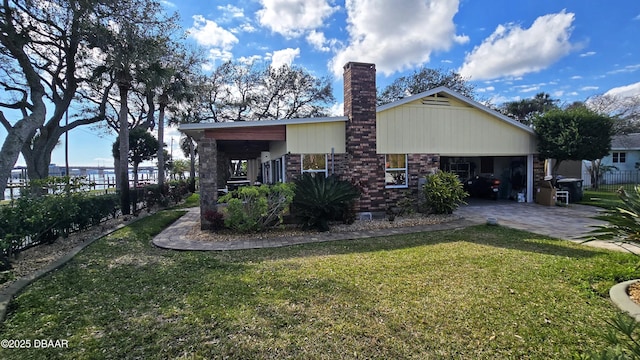 rear view of house with fence, a lawn, a chimney, decorative driveway, and a garage