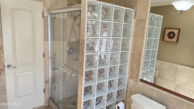 bathroom featuring a stall shower, toilet, and tile walls