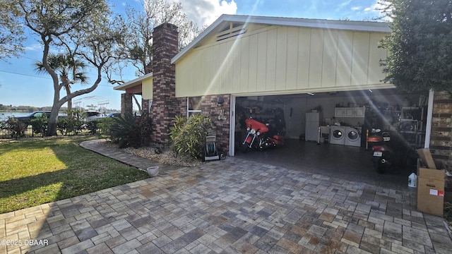 view of side of home with decorative driveway, a yard, an attached garage, and a chimney