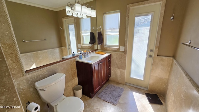 bathroom with vanity, a wainscoted wall, crown molding, tile walls, and toilet