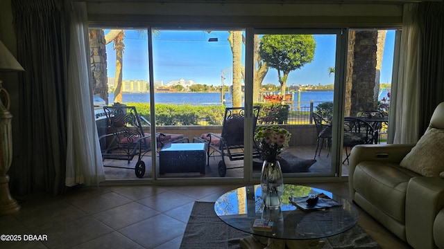 living area with tile patterned flooring, a wealth of natural light, and a water view