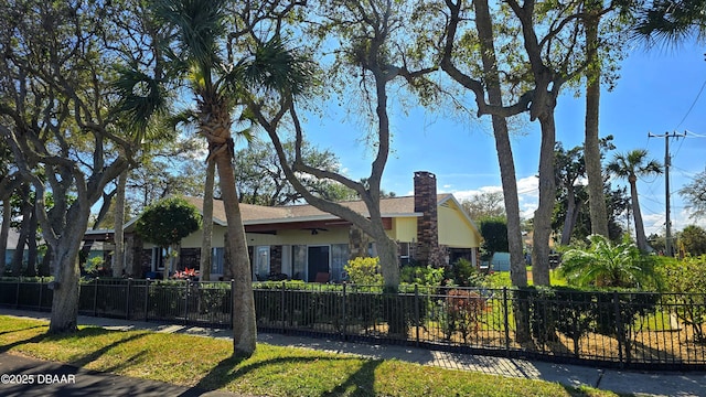 view of front of home with a fenced front yard, stone siding, and a chimney