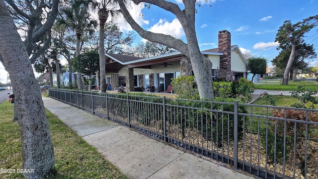 exterior space with ceiling fan, a chimney, and fence