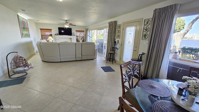 living room featuring visible vents, light tile patterned flooring, a fireplace, baseboards, and ceiling fan