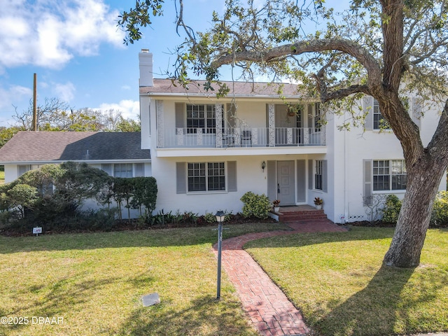 view of front of home with a front yard and a balcony