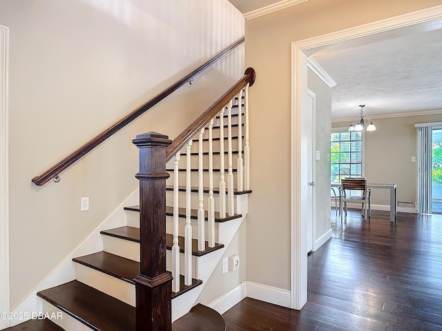 stairway with hardwood / wood-style floors, crown molding, and an inviting chandelier