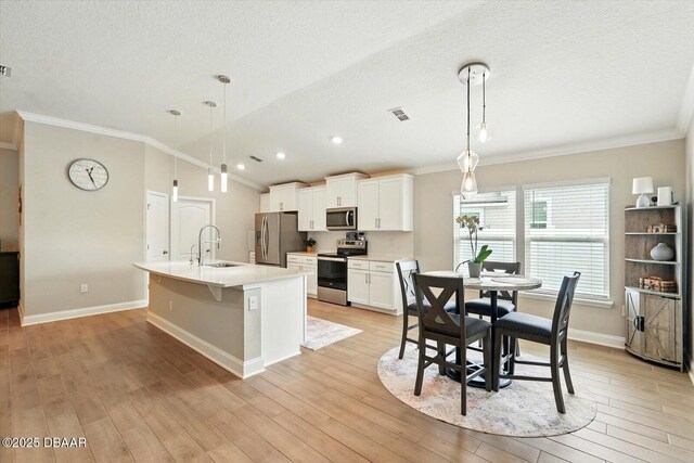 52 Lumber Jack Trl, Palm Coast, FL 32137 - kitchen featuring appliances with stainless steel finishes, crown molding, a sink, a kitchen island with sink, and baseboards