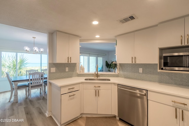 kitchen with backsplash, white cabinetry, light wood-type flooring, and appliances with stainless steel finishes