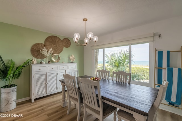 dining area featuring a textured ceiling, an inviting chandelier, and light hardwood / wood-style flooring