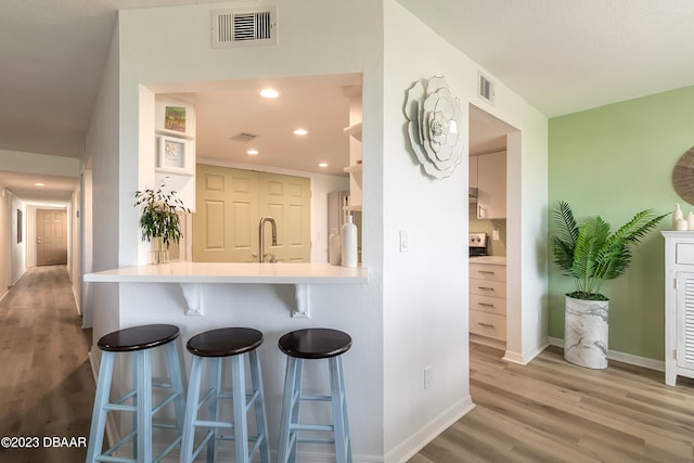 kitchen featuring kitchen peninsula, sink, hardwood / wood-style flooring, and a kitchen breakfast bar