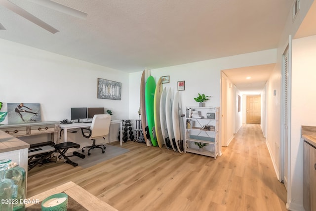 office area with ceiling fan, a textured ceiling, and light hardwood / wood-style flooring