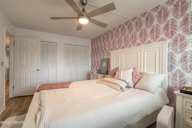 bedroom featuring ceiling fan, light wood-type flooring, and two closets