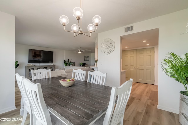 dining area with light hardwood / wood-style floors and ceiling fan with notable chandelier