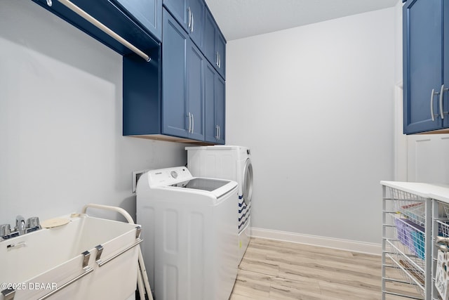 laundry room featuring cabinets, washing machine and dryer, and light wood-type flooring