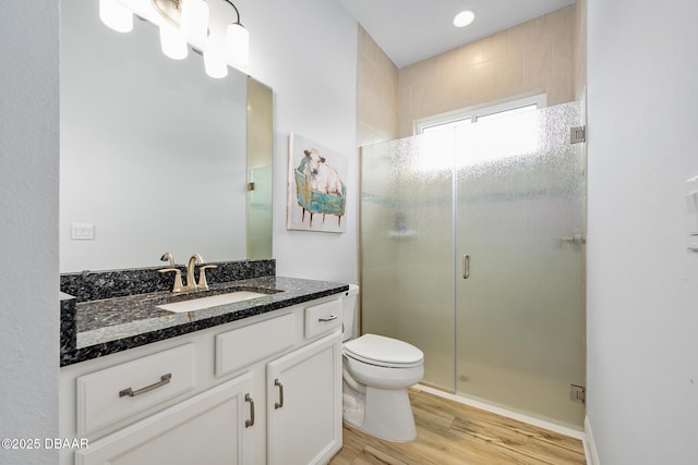 bathroom featuring hardwood / wood-style flooring, vanity, toilet, and a shower with shower door