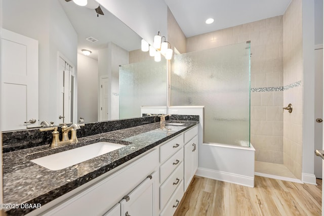 bathroom featuring wood-type flooring, tiled shower, vanity, and ceiling fan