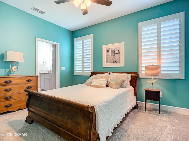 carpeted bedroom with multiple windows, connected bathroom, and ceiling fan