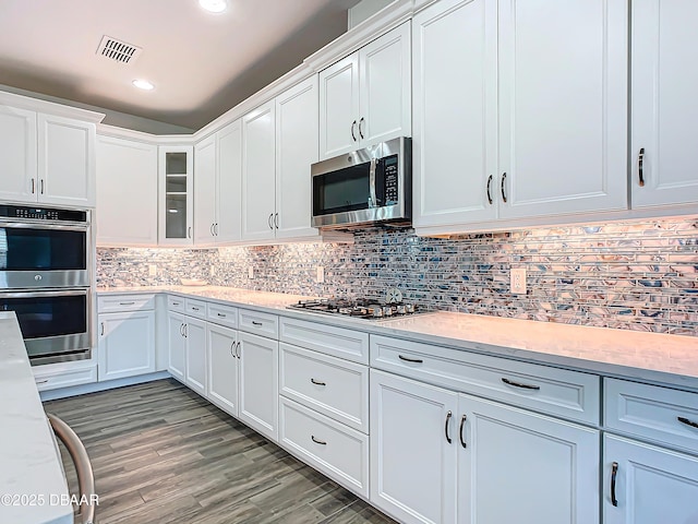 kitchen with backsplash, light hardwood / wood-style floors, white cabinetry, and stainless steel appliances