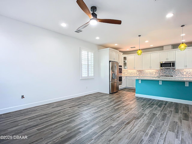 kitchen featuring a breakfast bar, white cabinets, stainless steel appliances, and decorative light fixtures