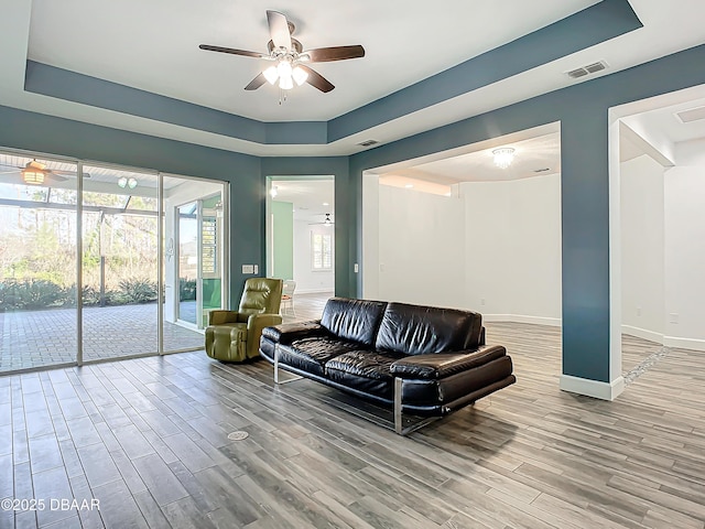 living room with a tray ceiling and ceiling fan