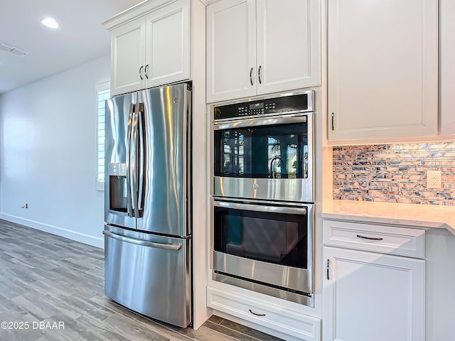 kitchen featuring light hardwood / wood-style floors, white cabinetry, backsplash, and appliances with stainless steel finishes