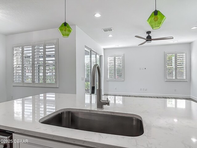 182 Island Breeze Ave, Daytona Beach, FL 32124 - kitchen view of a sink, ceiling fan, hanging light fixtures, recessed lighting, and light stone counters